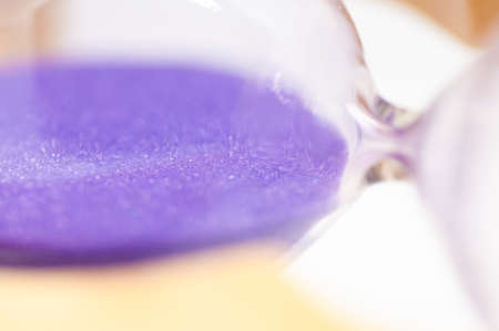 Lilac hourglass on white background. Macrophotography of sandglass.の写真素材