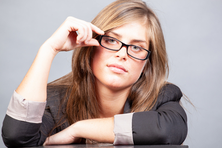 Woman with glasses in the office on grey backgroundの写真素材