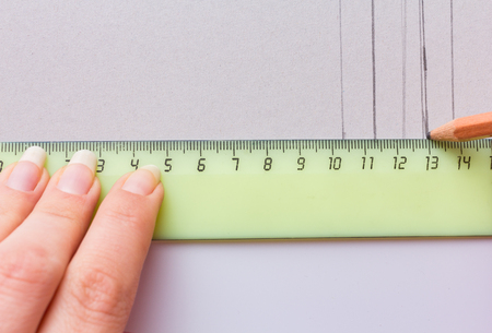 woman hands with long nails drawn projects with pencil and ruler on a white paper, mockups close-upの写真素材
