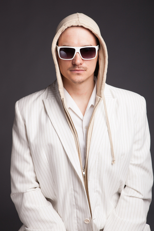 Portrait of a young man in the hood wearing shade on dark grey backgroundの写真素材