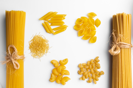 variety of italian raw dry pasta spaghetti, penne rigate, vermicelli, lumaconi rigati, conchiglie and cellentani on white desk background. top view.の写真素材