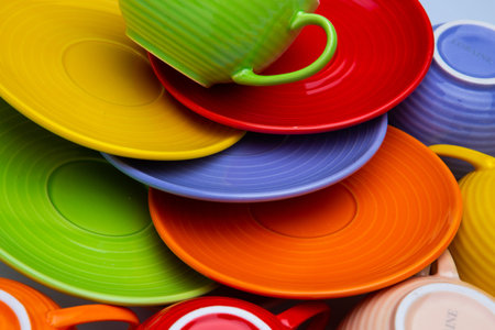 Set of colorful red, green, blue, biege tea and coffee cups and plates or dishes closeup on white...