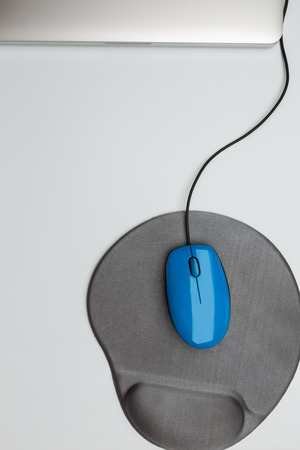blue mouse and pad and aluminium chasis of notebook computer on white background, top view, copy space, work on computerの写真素材
