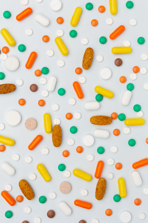 medicine drug pills and capsules medications of different color and shape on white background, closeup, top view, verticalの写真素材