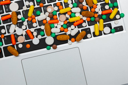 medicine drug pills and capsules of different type and color on computer keyboard closeup, on white...