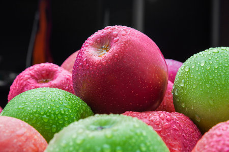 heap of fresh clean green and red apples with drops of water mix on black background, top side view...