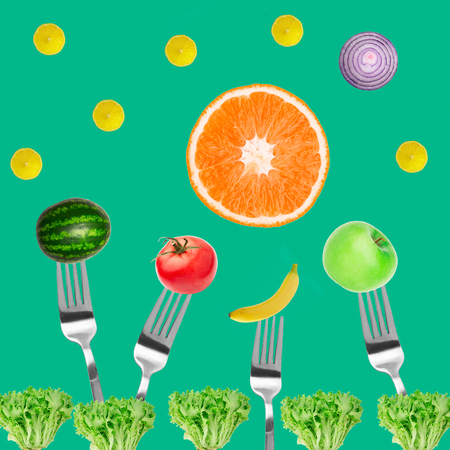 vegetables and fruits on fork Top view Composition of tomatoes, apples, banana, lemon and orange, watermelon on mint green backgroundの写真素材
