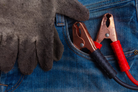 metal electric red and black clamps and dirty protective gloves for emergency car start in blue...
