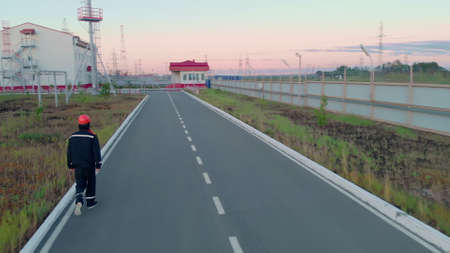 A worker in a helmet makes a round of the industrial territory around the perimeter, behind the fence, the tundra, oil and gas fieldsの写真素材