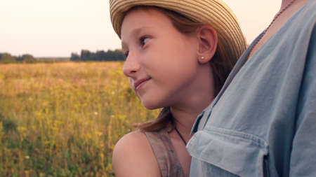 A beautiful teenage girl in a hat, gently snuggled up to her mother. Daughter hugs mom with love. Relationship in the family.の写真素材