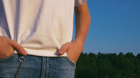 The teenage guy puts his hands in the pockets of dirty jeans. The hipster jeans are embellished with a chain. Teenage life.の写真素材