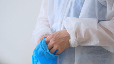 Doctor putting on protective blue gloves. A medical worker puts on blue gloves before working with...