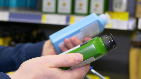 A man holds two shower gels in his hands, reads the composition and chooses the best one for himself. Shopping for toiletries in a supermarket, a man chooses a shampoo and lays down a purchaseの写真素材