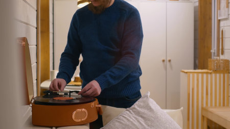 A man puts a record in a gramophone to listen to classical music. A vinyl record of classical music is used in a gramophone player. Put on a record to listen to musicの写真素材