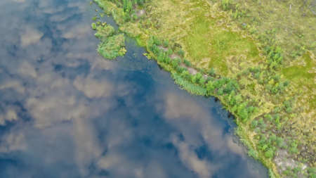 Aerial view of the lake in which fluffy clouds are reflected in the sky. Lonely lake in a swampy area. A beautiful lake far away from civilization.の写真素材