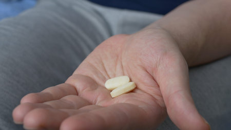 Two yellow tablets are poured on the palm of the hand to treat serious diseases. The patient takes...