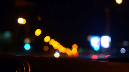 Out of focus road lights. View of the night road where cars move and lights blink in a beautiful bokeh. Unrecognizable night road with traffic and city lights. Yellow and red lights out of focus.の写真素材