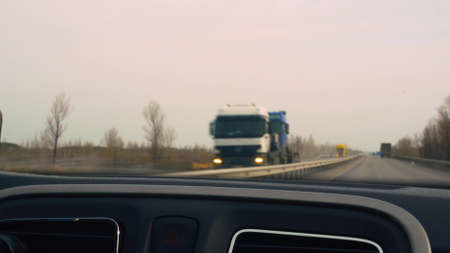 A car ride along the highway, the view from the car interior to the windshield while driving at high speed towards the flow of trucks and other cars in blur. Video from the windshield in motion.の写真素材
