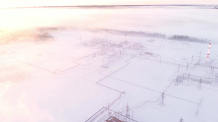 A drone flies over an oil and gas field in siberia in winter. There is fog over the oil and gas production plant due to the extremely low air temperature. Fuel crisis in Europe and America.の写真素材