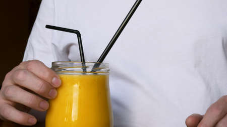 Close-up shot of a full glass of smoothie, from a glass cup eat a yellow mango smoothie with a spoon. Consumption of vitamins from fresh fruits to maintain good health and mood.の写真素材