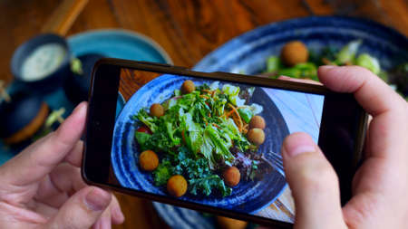 The blogger takes a photo of his lunch on his smartphone to share it with his followers on social networks. Photographing food is a new trend in social networks. Healthy food is popularized.の写真素材