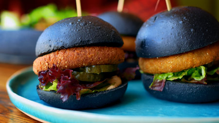 An American in a restaurant eats burgers with a black bun. Eating unhealthy foods high in trans fats...