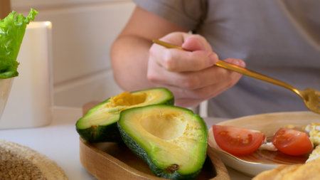 Healthy breakfast on a keto diet with a lot of oil, fresh avocado and eggs with white sauce. A man eats a full meal for breakfast, energizing for the whole day. Food intake of polyunsaturated fats.の写真素材