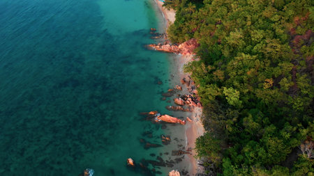 A cinematic video of a drone flying over a clear water beach. rocky tropical island for a relaxing...