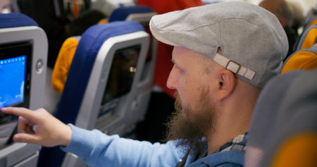 Airplane passenger waiting for flight, looking at travel map on Airplane seat screen. Cinematic shot passenger waiting for flight, waiting for other passengers. Concept: Waiting for flight in airplaneの写真素材