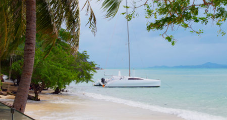 Cinematic video moored yacht sway on waves in ocean Asia before rain Yacht sway on waves in ocean shore rainforest before rain Concept weather before summer tropical rain, yacht in shore sway on wavesの写真素材
