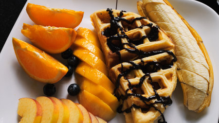 Delectable Breakfast: Drizzling Vienna Waffles and Fresh Fruits with Chocolate Syrup. Enjoy delightful morning feast as rich chocolate syrup is poured generously over Vienna waffles and fresh fruitsの写真素材