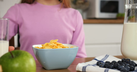 Woman gracefully pouring milk into cereal cinematic slow motion start of family breakfast Cereal is...