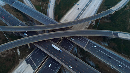 Cars driving along freeway go to exits from multi-level interchange. Top view from drone. Modern...