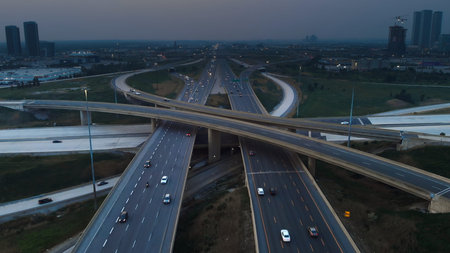 Cars navigating multi-level interchange in America. Evening aerial footage captures intricate beauty...