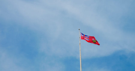 Fluttering British colony flag, vivid against blue sky, symbolizes historic pride, enduring legacy. National emblem waves, reflecting past sovereignties, colonial history. Not official Flag of Canadaの写真素材