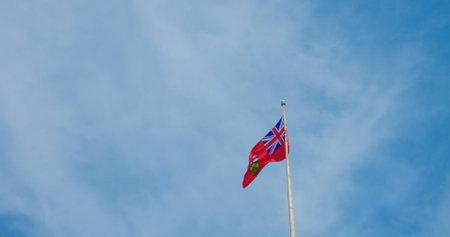 Fluttering British colony flag, vivid against blue sky, symbolizes historic pride, enduring legacy....