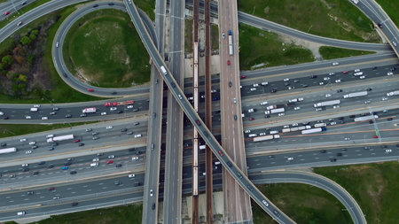 Elevated metro glides past cars on bustling highways, fusion of rail and road commute. City's pulse...