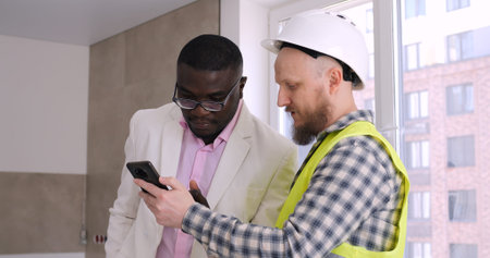Black man collaborates with builder, using smartphone to plan and negotiate price for his home...