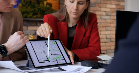 Tyumen, Russia - April 23, 2024: Team shows apartment layout to client on sleek tablet screen. Woman...
