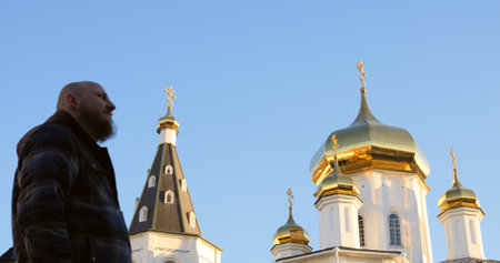Man crossing himself in front of golden-domed Orthodox church, symbolizing faith, prayer, and devotion in serene spiritual moment. crossing himself reflects deep religious tradition and inner peace.の写真素材