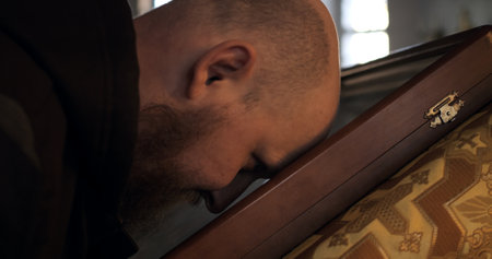 Man kissing icon on church altar, expressing deep reverence and faith. Spiritual devotion in sacred space, emphasizing connection with religion and tradition. Man touching sacred relic in churchの写真素材