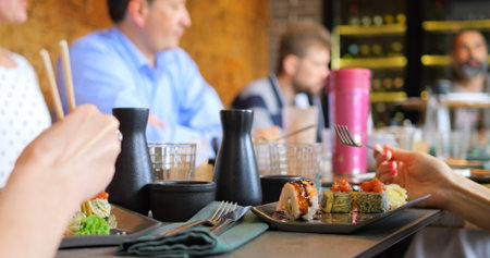 Modern dining with Japanese cuisine. Group enjoying Japanese cuisine with sushi rolls served fresh...