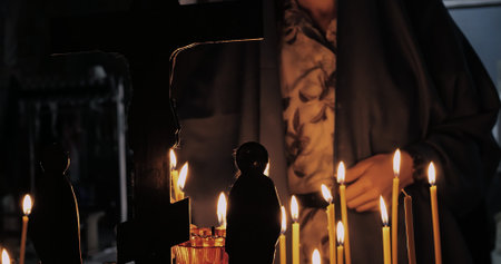 Traditional act of lighting candles during religious rituals, symbolizing hope, faith, and spiritual...