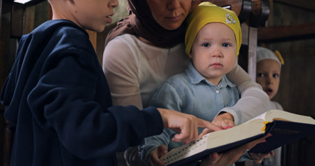 Mother with her children gathered in church, teaching them faith and spirituality. Family shares moment of connection, reading Bible together in sacred space of worship. Family valuesの写真素材