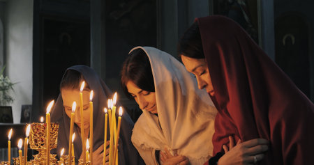 Women participating in lighting candles during deeply meaningful spiritual ceremony that emphasizes importance of community togetherness and unity among individuals within their shared traditionsの写真素材