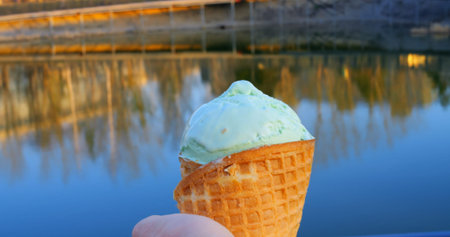 Delicate pistachio ice cream nestled in crispy waffle cone, suspended against tranquil lake...
