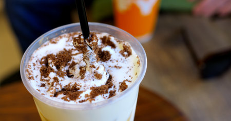 Skilled barista sprinkling cocoa powder over whipped cream, creating artistic latte design with precise dark straw garnishing techniqueの写真素材