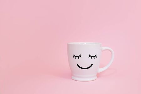 Happy friday word. Cup of coffee on pink background with smile face on mug.の写真素材