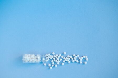 homeopathic globules and glass bottle on blue background. Alternative Homeopathy medicine herbs, healtcare and pills concept. Flatlay. Top view. copyspace for text.の写真素材