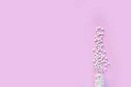 homeopathic globules and glass bottle on pink background. Alternative Homeopathy medicine herbs, healtcare and pills concept. Flatlay. Top view. copyspace for text.の写真素材
